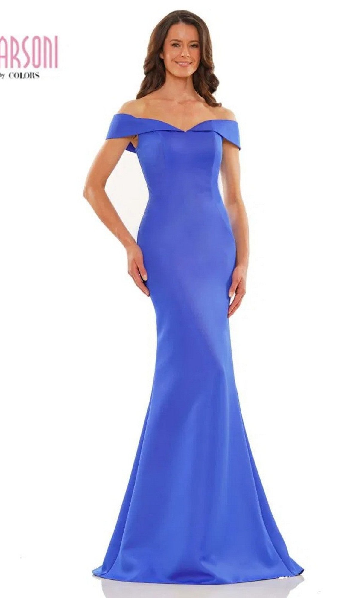 A woman stands smiling against a white background, wearing the Marsoni MV1153 long formal dress in royal blue, featuring an off-the-shoulder neckline, fitted bodice, and flared hem.